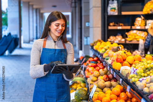 Fotografie Happy woman using tablet checking inventory at fruit stand