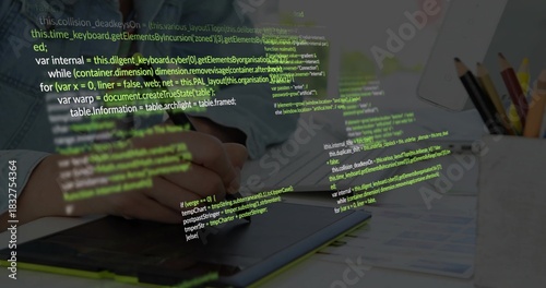 Working hands in denim shirt, using stylus editing on graphics tablet at desk, code overlay