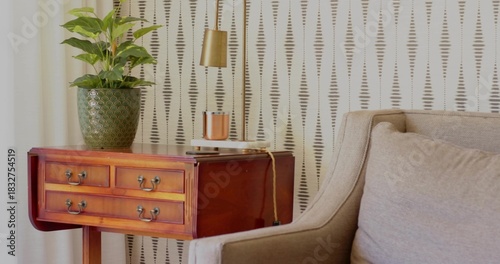 Wooden side table showing green planter, brass lamp, notebook with cable in lounge nook, copy space