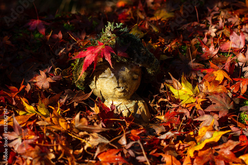 Tiny jizo statue at buddhist temple Sanzen-in in Kyoto during red leaves season