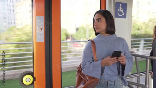 Young woman standing and using a smartphone on public transport