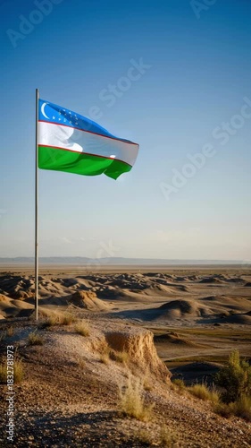 The Uzbek flag stands tall against the backdrop of golden desert dunes, highlighting the beautiful blue sky. This scene captures the essence of Independence Day and national pride in Uzbekistan.