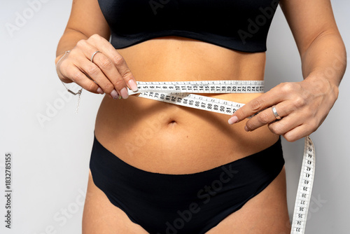 Woman measuring waist with tape for weight loss
