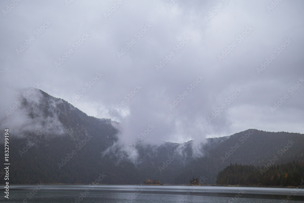 Fototapeta premium Cloudy mountain landscape with mist over the lake