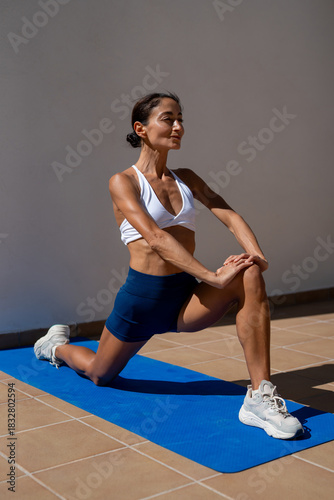 Konstfotografi Athletic woman stretching hip flexors on yoga mat outdoors, performing deep lung