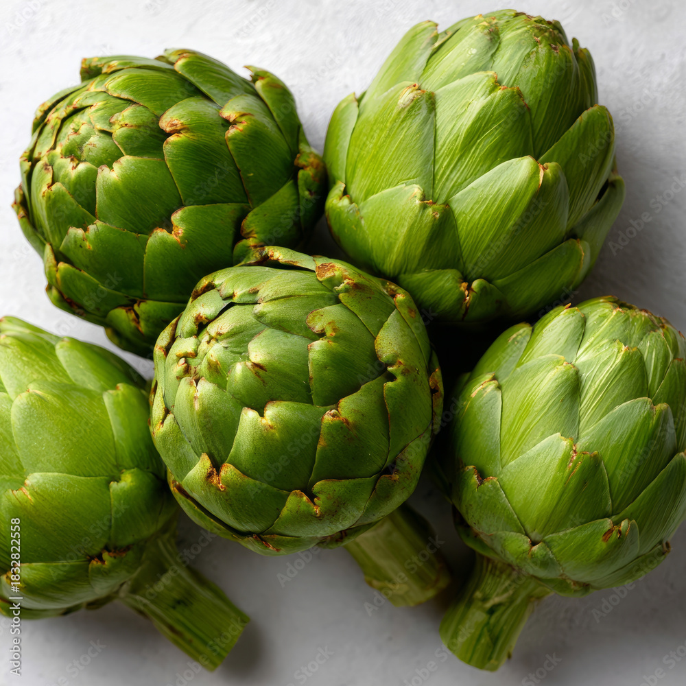 Obraz premium Fresh green artichokes displayed on a light surface.