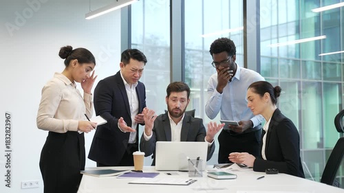 Group of disappointed businesspeople read bad news on laptop computer sitting at workplace in business office. Frustrated worried colleagues co-workers are upset reviewing negative financial results