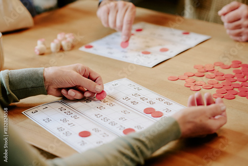 Quadro su tela Senior Caucasian woman and senior Caucasian man playing bingo at table, hands pl
