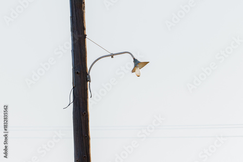 A solitary street lamp on a wooden pole against a clear sky.