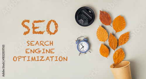 SEO concept with autumn leaves, clock, and coffee cup on a neutral background for digital marketing
