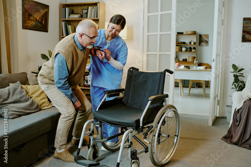 Tableau sur toile Senior Caucasian man with disability being assisted by young adult Caucasian wom