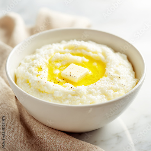 Creamy white grits topped with melted yellow butter in a white bowl