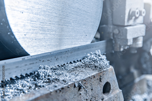 Close-up scene: A band saw cutting metal shaft parts in blue tones. copy space