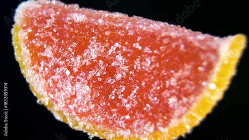 Citrus Fruit Slice Gummy Candy rotating close up. Macro of Orange or Grapefruit wedge marmalade covered in sugar. Vitamin C concept.