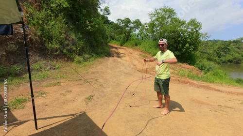 Man unwires solar panel cables at rustic lakeside campsite in Jalisco, Mexico