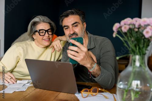 Mature couple planning home finance with laptop and smartphone