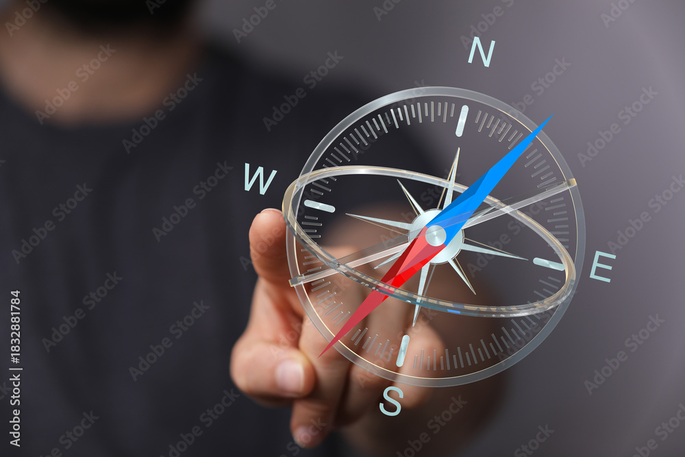 Fototapeta premium A close-up of a hand pointing at a modern compass design, embodying direction, guidance, and the concept of finding your way in the digital worl
