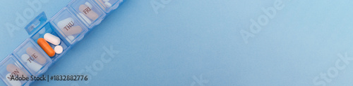 Wallpaper Mural Blue plastic pill organizer with orange and white capsules on blue background. The concept symbolizes daily healthcare routine, organization and personal wellness planning. Web banner, copy space Torontodigital.ca