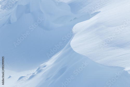 Curved edge of pale blue snowdrift and shadow in winter landscape