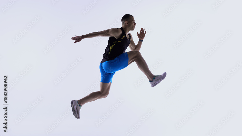 Obraz premium Athlete jumping forward in extended mid-stride. Concept of stride-length drills, mid-air control training, power-stride technique lessons, athlete development modules.