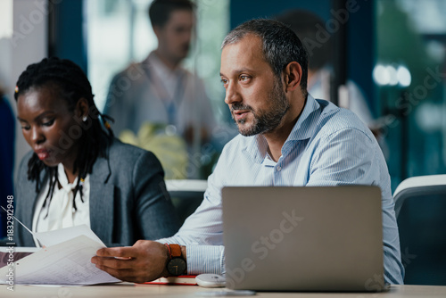 Senior Management Team Leading New Employee Feedback Session in Modern Open Plan Office