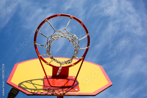 Wallpaper Mural A red and yellow basketball hoop against a blue sky, viewed from the bottom up Torontodigital.ca