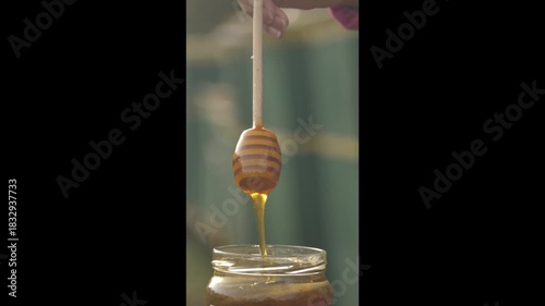 Natural Honey Pouring from Wooden Spoon into Jar