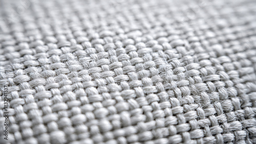 Detailed macro shot reveals the intricate plain weave of light gray fabric. Individual threads interlace precisely, creating a textured, durable textile surface.