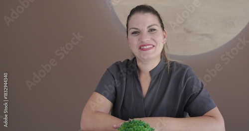 Young chiropractor woman smiling on camera at reception desk of private clinic - Therapist concept 