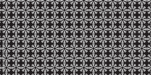 A seamless pattern of white, intricate snowflake shapes arranged in a uniform grid on a black background, creating a crisp and elegant winter-themed design.