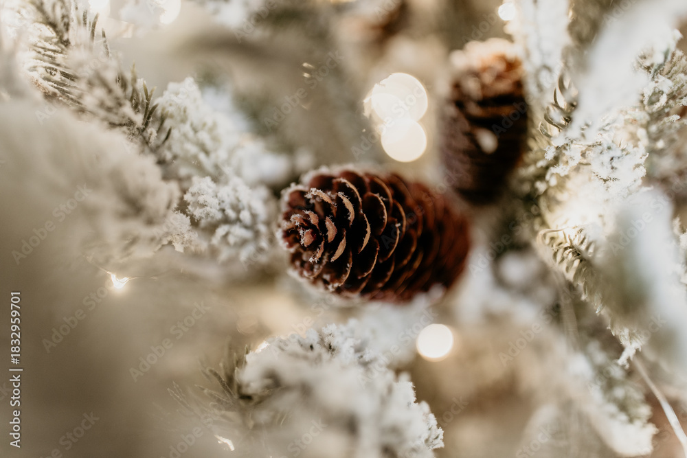 Obraz premium Snow-Covered Pinecone on Frosted Christmas Tree with Lights
