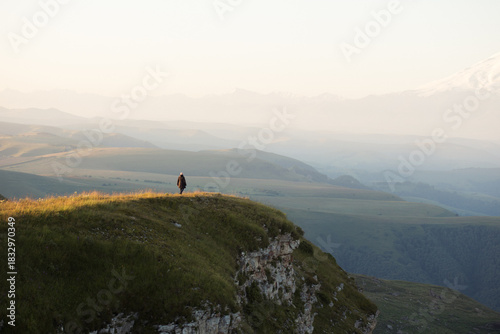 A woman walks along a hill with mountains in the background at dawn. man and nature are one