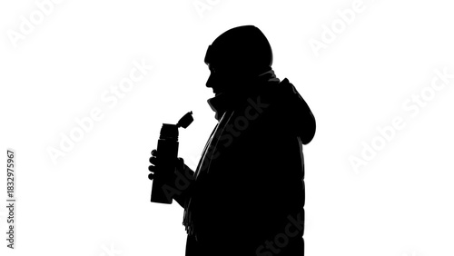 Silhouette of man holding bottle and wearing winter coat  