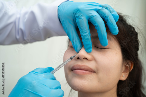 Asian woman receiving plastic surgery shape of nose performed on face.
