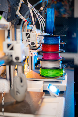 row of colorful 3d printing filament PLA material on environmentally friendly and recyclable paper cardboard spools on black carbon fiber background. modern FDM printer technology concept