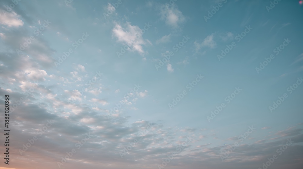 Obraz premium a serene image of a blue sky filled with soft, fluffy clouds. The sky transitions from a lighter shade to a deeper blue, creating a sense of peace and tranquility