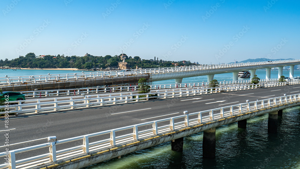 Obraz premium Scenic bridge over water with clear blue sky and distant land