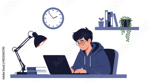 Young man with glasses working or studying on a laptop at his desk in a cozy, modern workspace with a lamp and books.