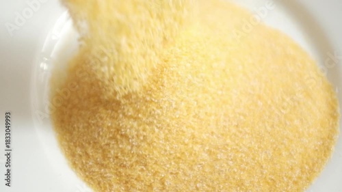 Closeup video of corn flour in a bowl. Yellow corn flour pile rotating in a bowl. Whole food source of carbohydrates.