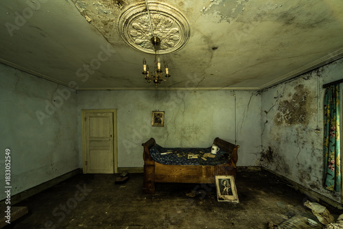 Photos Abandoned bedroom with antique wooden bed, cracked ceiling rose and chandelier,