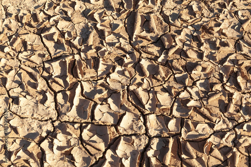 Dried desiccated mud texture in the bottom of an empty dam during a drought, environmental issues, climate change, global warming, natural disaster