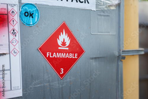 Flammable liquid warning sign on the chemical containment gallon. Industrial safety sign on the object, close-up with selective focus.