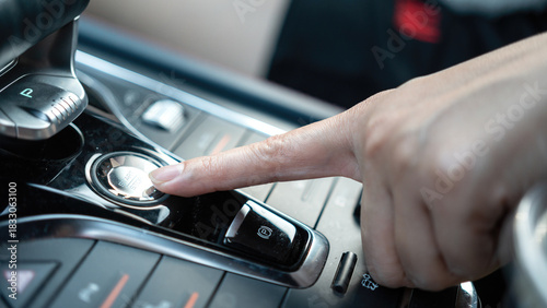 Action of a car driver's finger is pressing on engine start button of the modern sport car. Close-up with selective focus.