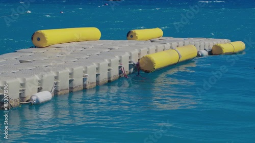 A modular plastic dock snakes through the waves, demonstrating the flexibility and stability of a floating pontoon. The HDPE modular elements bend and sway smoothly under the pressure of the waves