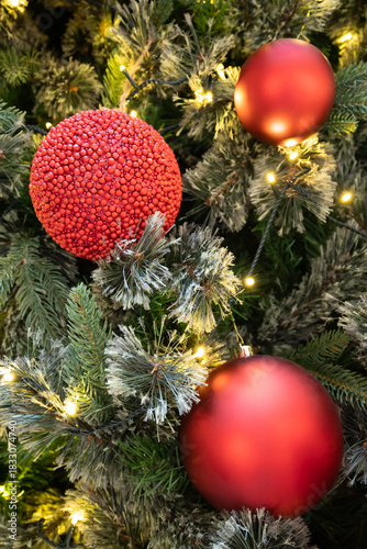 A lush Christmas tree adorned with bright red ornaments and twinkling warm lights creates a cozy holiday ambiance