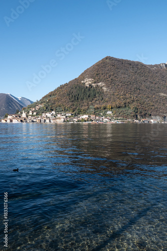 Coastal view of Montisola on Lake Iseo, with the island’s waterfront, boats, and surrounding mountains creating a peaceful and picturesque northern Italian lakeside scene.