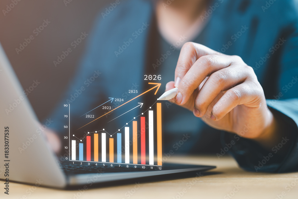 © Nirusmee - Businessman using a laptop to create a 2026 business plan, focusing on goal setting, organizational direction, objectives, and targeting new opportunities for future growth.
