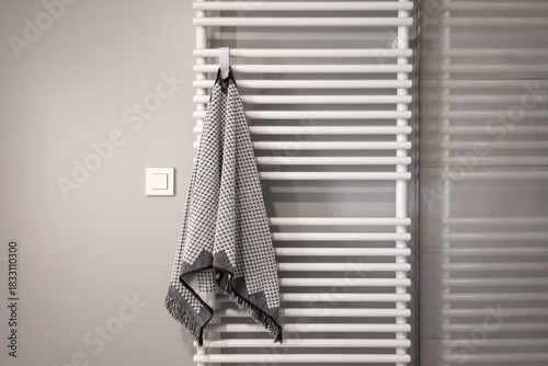 minimalist bathroom in white and grey colors with radiator and towel on it. bathroom interior with clean empty space