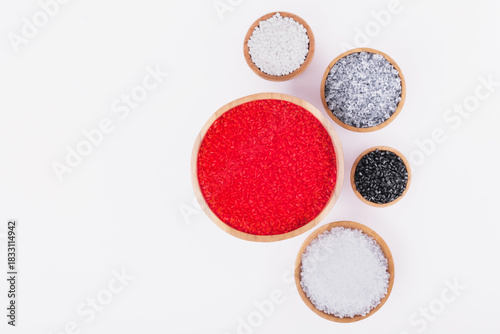 Polymer products of different colors in wooden containers on a white background. Polymers and polystyrene. Chemical industry