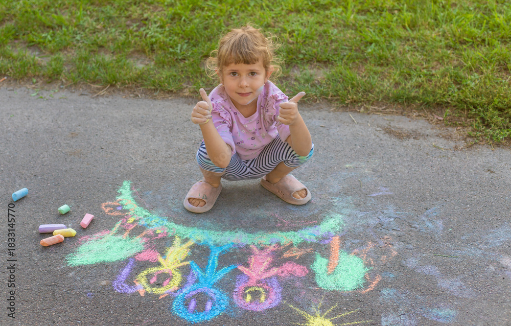 Fototapeta premium Children drawing with chalk on the asphalt. Selective focus.
